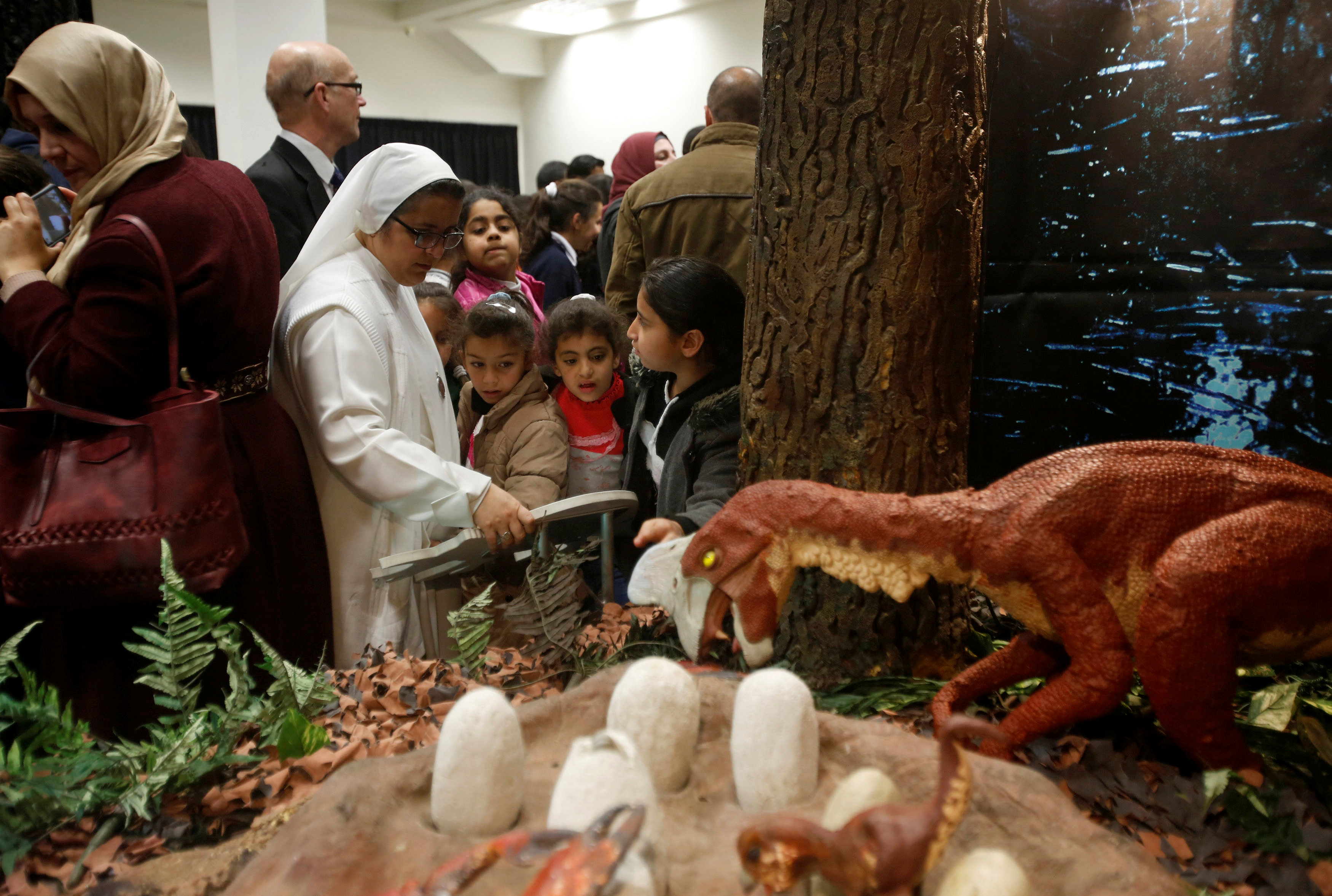 Palestinian children and visitors look at models of dinosaurs, which were donated by Henry Lowe to Bethlehem-Bath Links, during the opening of a dinosaur exhibition arranged by a Bath charity in the West Bank city of Bethlehem